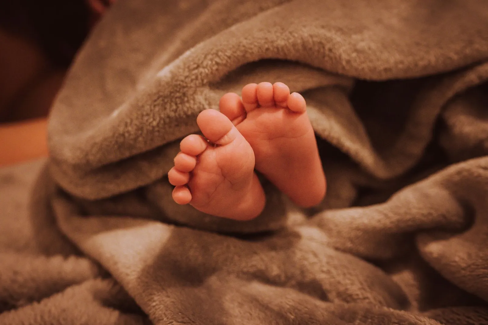 Tiny newborn feet wrapped in a warm blanket